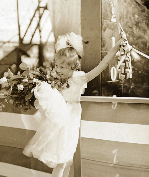 photo of young girl posing with a champagne bottle at ship christening